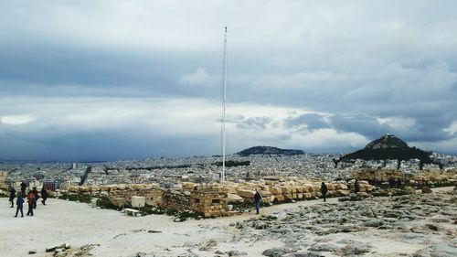 People standing on mountain against cloudy sky