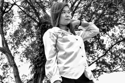 Low angle view of woman standing against trees