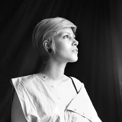 Low angle view of thoughtful mid adult woman looking away while standing in darkroom