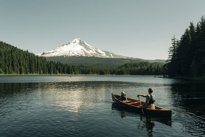 A father canoes with his daughter on trillium lake near mt. hood, or.