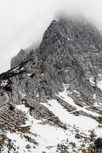 Tiny human walking on snow covered path under magnificent misty mountain