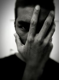 Close-up portrait of man covering face with hand