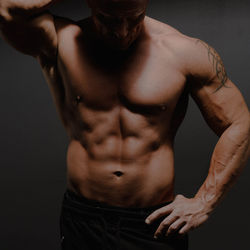 Midsection of shirtless man against black background