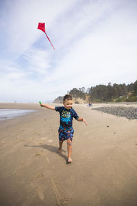 Young boy running with kite on oregon coast beach.