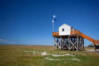 Built structure on field against clear blue sky