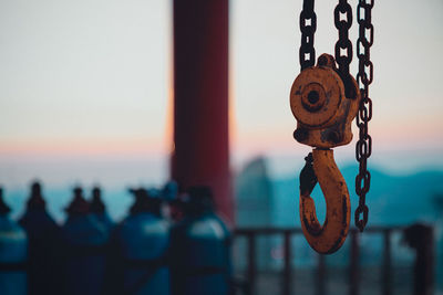 Close-up of chain hanging on railing against sky