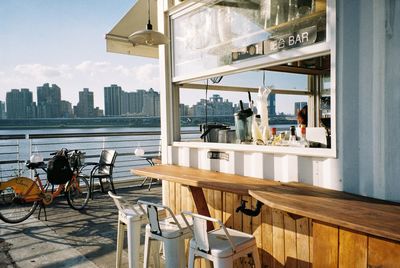 Chairs and tables in restaurant against buildings in city