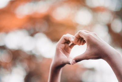 Close-up of person hand making heart shape outdoors