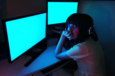 Side view of woman using computers in darkroom