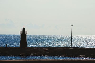 Lighthouse by sea against sky