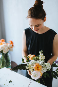 High angle view of woman arranging flowers in vase at table