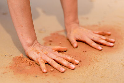 Cropped image of hands playing with sand at beach