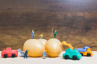 Close-up of figurines with eggs and toy trucks on table