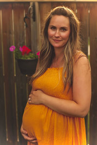 Portrait of smiling pregnant woman standing in yard