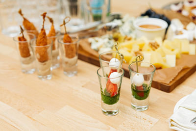 Catering, food and drinks concept - close up of different appetizers in glasses on table