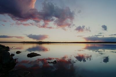 Reflection of clouds in calm lake at sunset