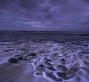 Scenic view of beach against storm clouds at dusk