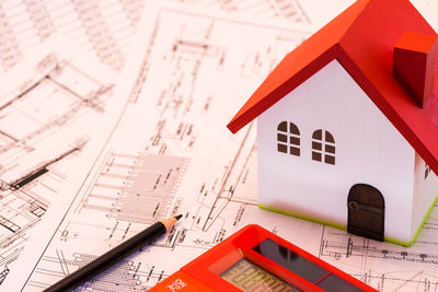 Close-up of model house and calculator on blueprints