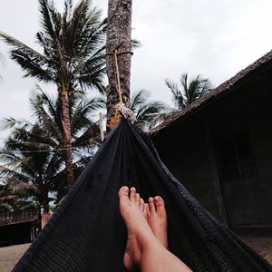 Low section of man on hammock against sky