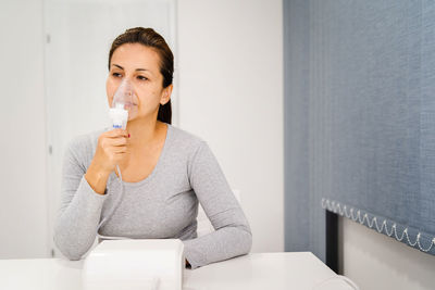 Woman holding nebulizer while sitting at table