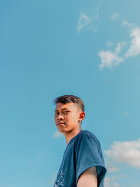 Portrait of boy looking away against blue sky