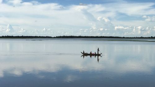 Man sitting on boat in sea against sky