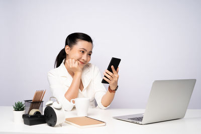 Young woman using smart phone against white background