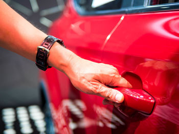 Midsection of man holding red car