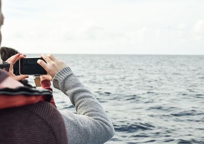Man photographing sea against sky