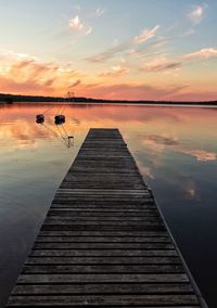 Pier over lake against sky during sunset