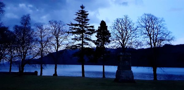 Silhouette trees by lake against sky