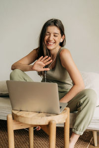 Young happy woman is using laptop and headphones for online conference.