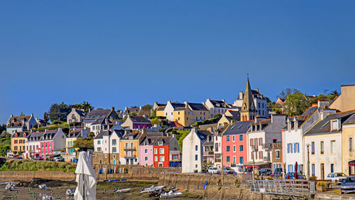 Buildings in city against clear blue sky