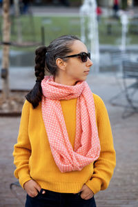 Woman wearing sweater and scarf looking away in city