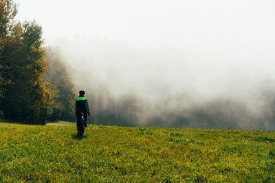 Rear view of man standing on grassy field