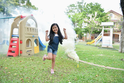 Full length portrait of cheerful girl playing at playground