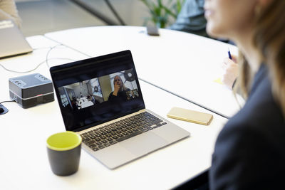 Midsection of businesswoman using laptop at table