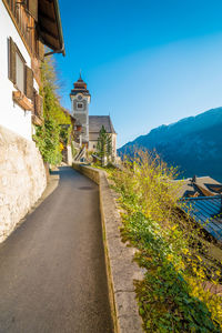 Road amidst buildings against clear blue sky