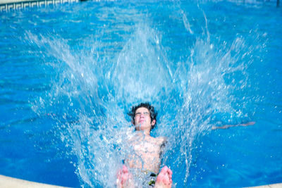 High angle view of shirtless teenage boy diving in swimming pool