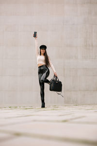 Woman wearing sunglasses against wall