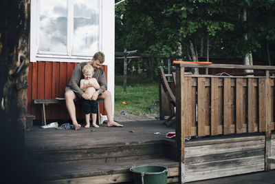 Father looking at son while sitting on bench during summer