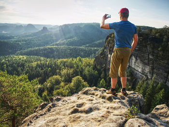 Smart phone mobile photography of spring hilly landscape. focus to man hands with phone