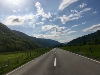 Road leading towards mountains against sky