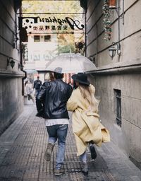 Rear view of women walking on street in rain