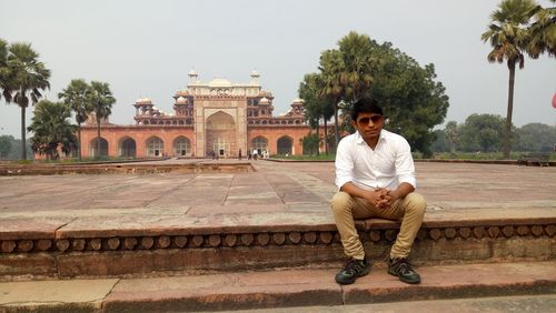 Portrait of young man sitting in front of jama masjid