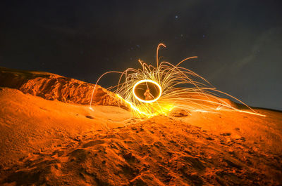 Illuminated ferris wheel on land against sky at night