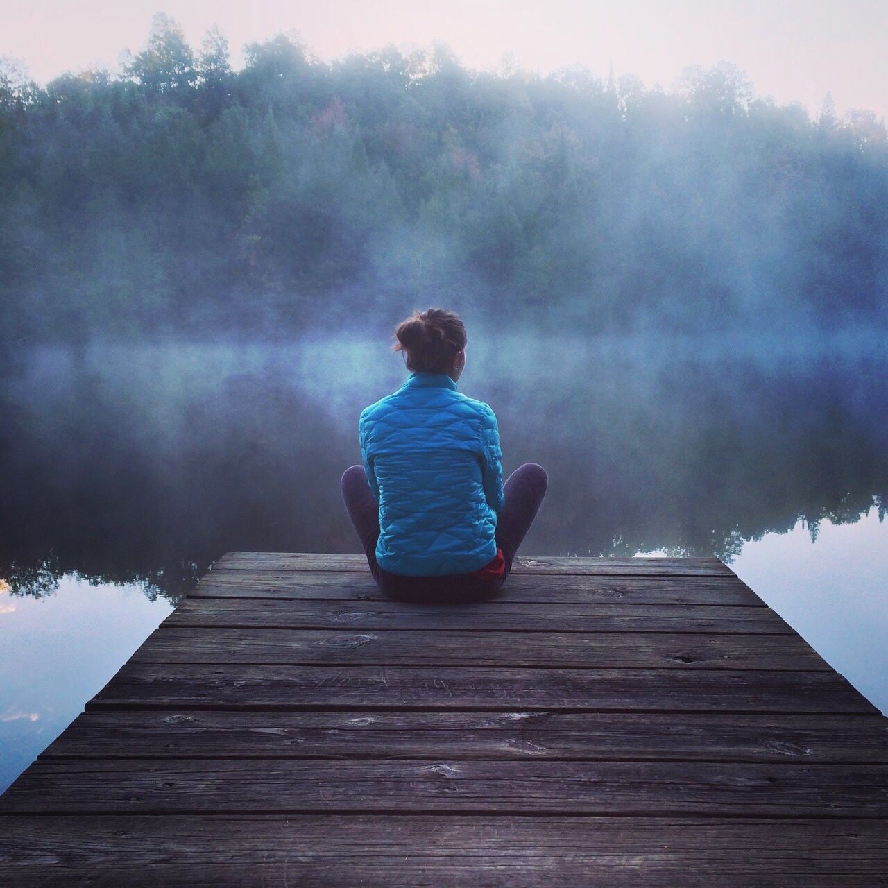 REAR VIEW OF MAN SITTING ON PIER AT LAKE