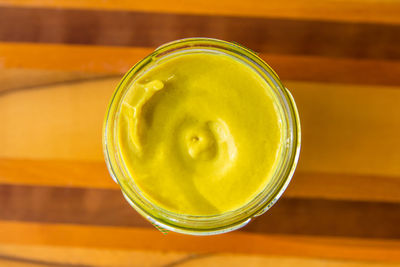 French mustard pot on warm wooden background shot from above