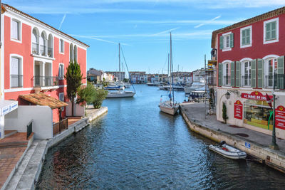 Boats moored at harbor against sky in city