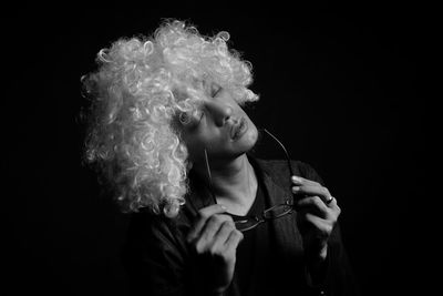 Portrait of man holding camera over black background